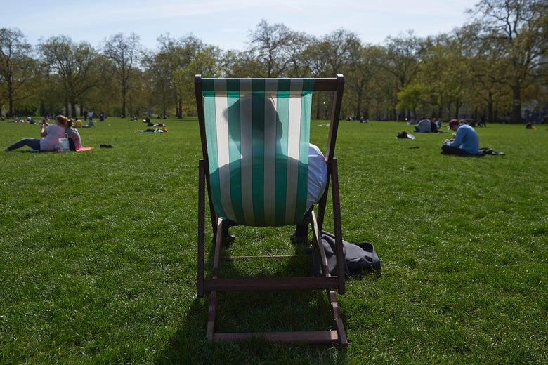 A man relaxes in a deck chair in the afternoon sunshine in the park.